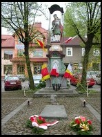 Dobczyce. Figura świętego Floriana w Rynku, udekorowana flagami Polski, Dobczyc i Małopolski.